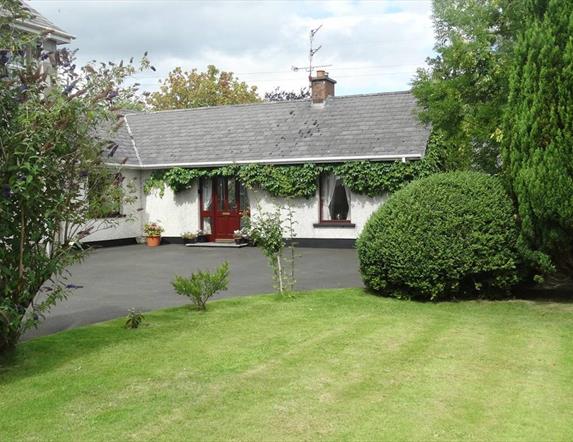 Outside of cottage, garden and trees in image