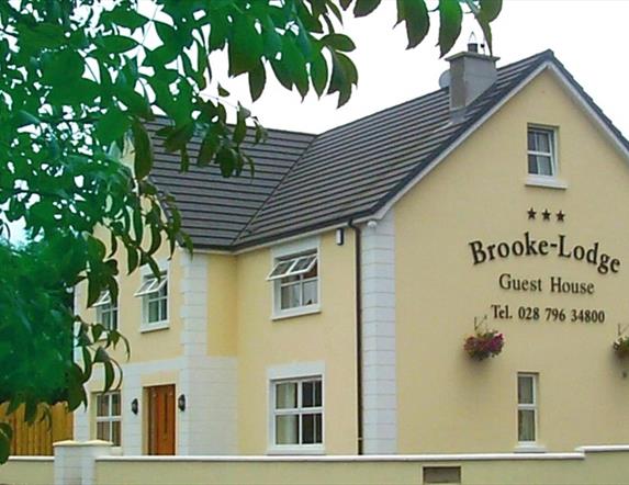 Outside of Brookelodge Guest House.  Yellow painted 2 storey detached house with wooden front door