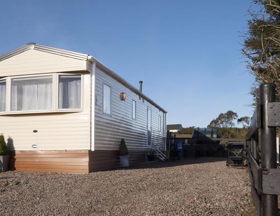 Image of the exterior of a static caravan and a stoned driveway