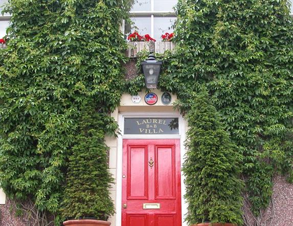 Outside image of Laurel Villa with greenery on walls and red door