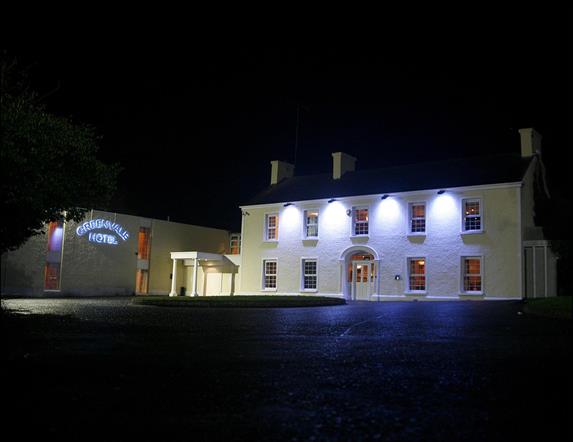 Image of a large two story building lit with four flood lights