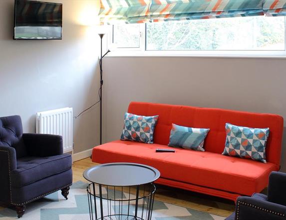 living area with orange sofa and 2 navy armchairs