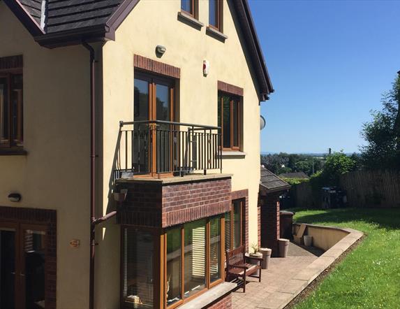 Outside of 2 storey yellow house showing patio doors to small balcony