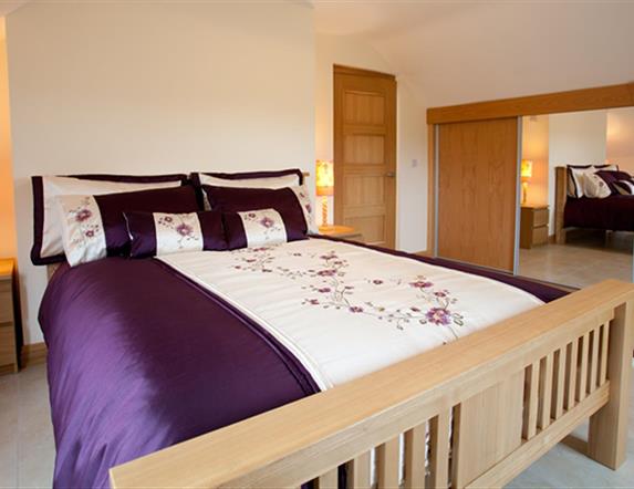 Double bedroom with sliding mirror wardrobe doors, double bed and bedside lockers