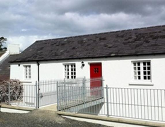 Outside of cottage with white exterior and red door