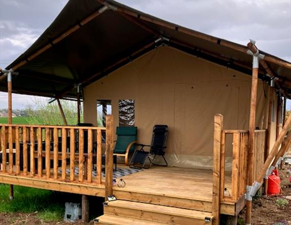 The outside of the tent with a covered deck and chairs