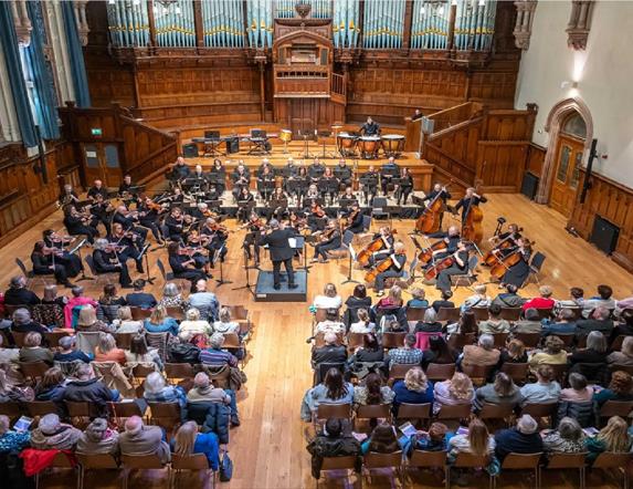 Image of the orchestra playing in front of an audience