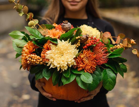 A pumpkin filled with autumnal flowers