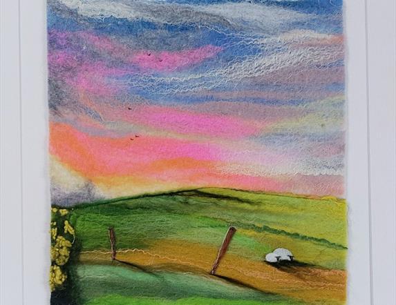 felt image of a colourful sky, fields ands sheep