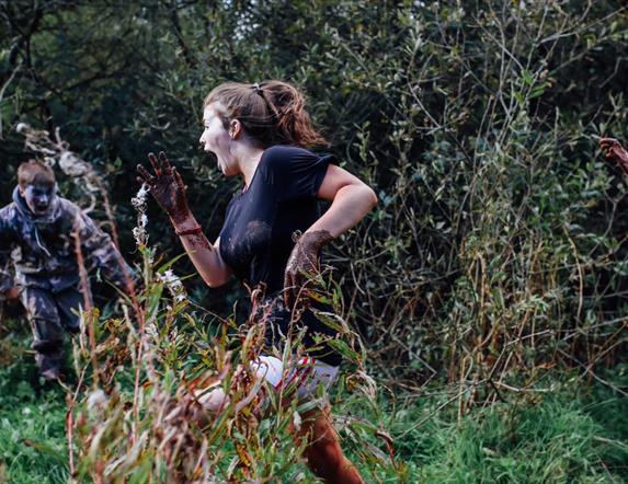 Two girls running away from a zombie