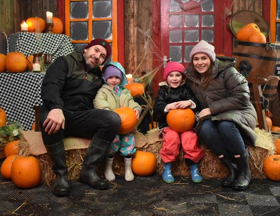 A family sitting on hay bales with Pumpkins