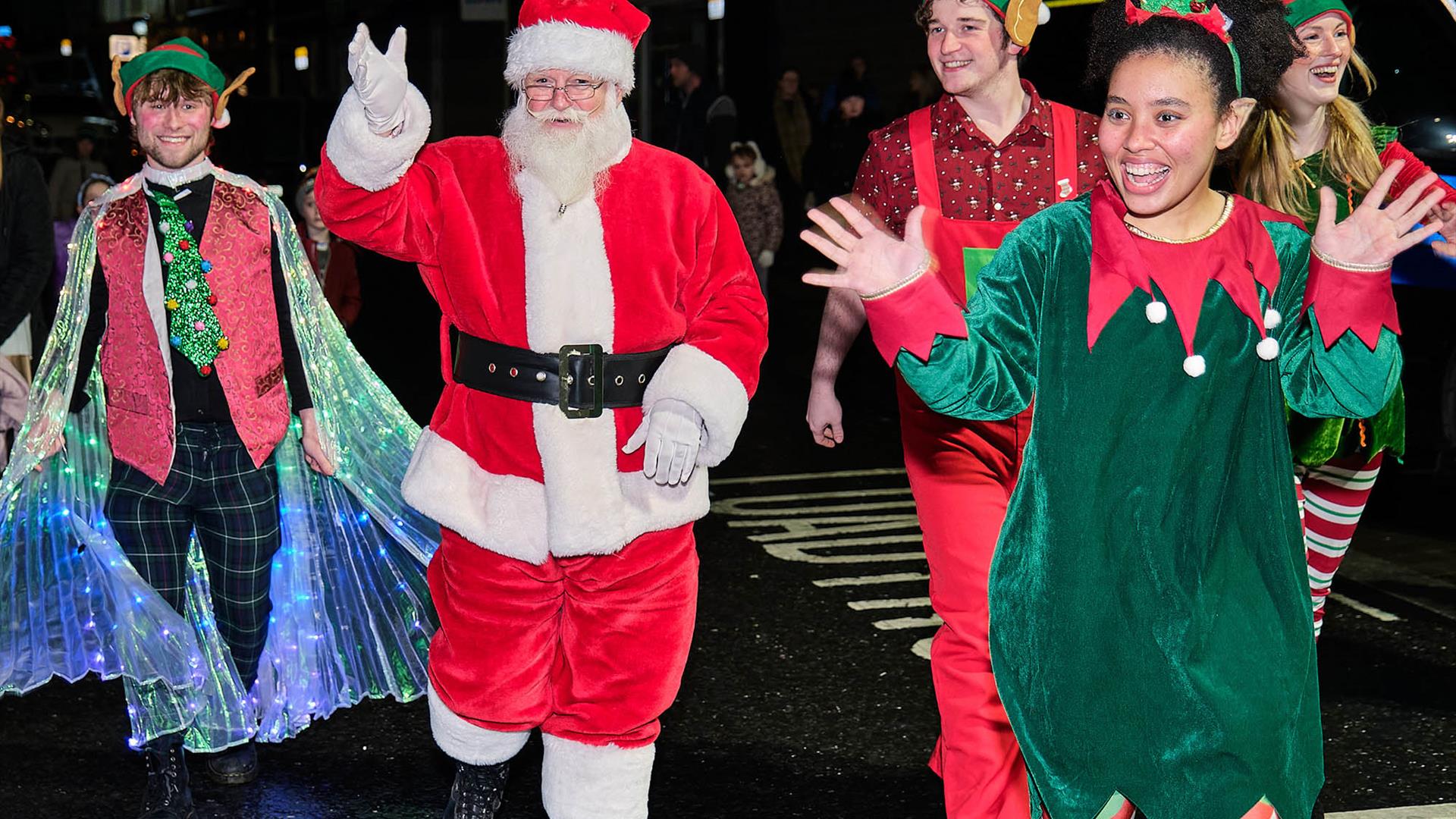 Santa walking with his elves waving