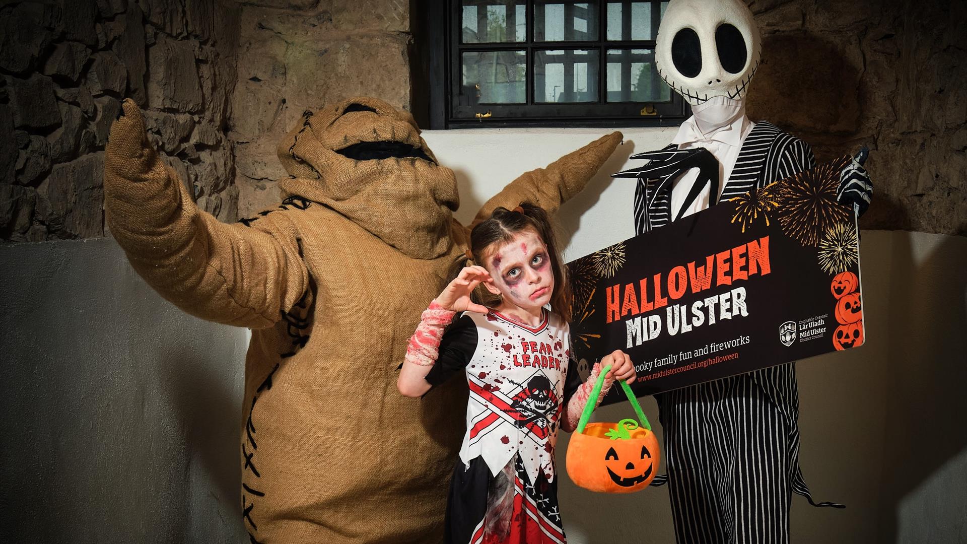 Mr Halloween and Sack man and a young girl dressed as a zombie cheerleader in a cell