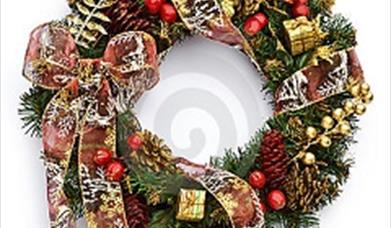 Image of a Christmas wreath with gold boxes, red bows and gold accessories.