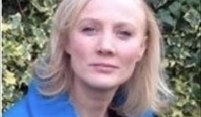 Image of Anne Quinn who has blonde shoulder length hair and wearing a blue jacket 