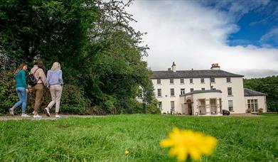 Three girls walking towards Lissan house on a sunny day