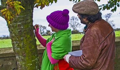 Brightly dressed lady and gentleman looking at tree