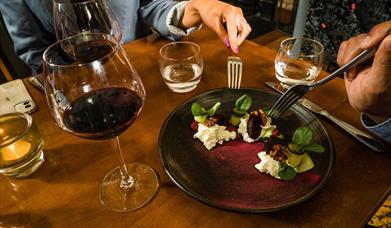 A plate of food and glass of red wine