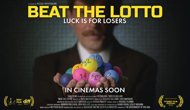 Image of gentleman in suit holding bright coloured lottery number balls