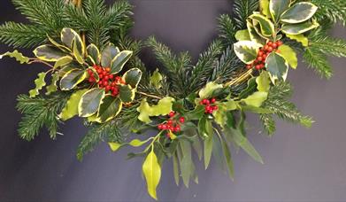 Image of Christmas wreath made using pine tree branches and holly plants. 