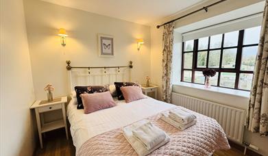 Double bedroom with pink accents and large window.
