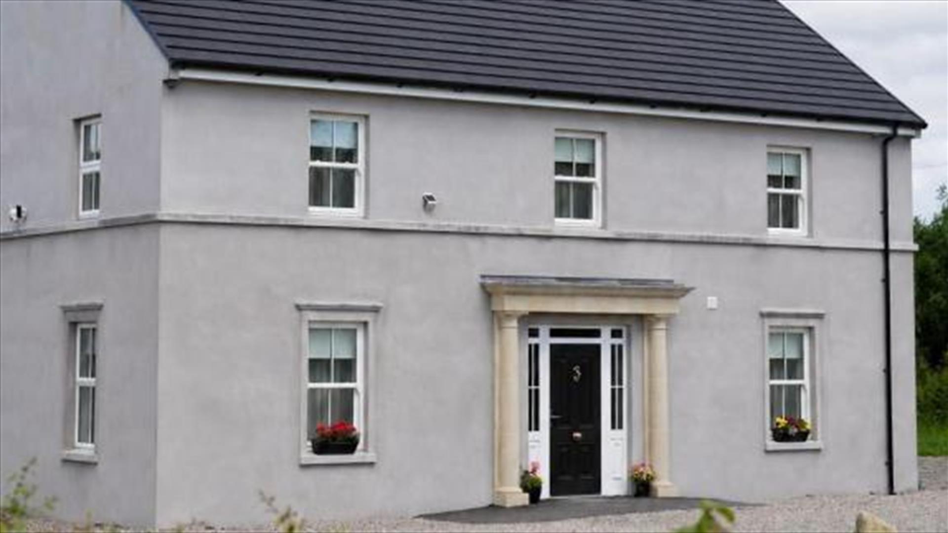 Carland Cottage exterior with gravel driveway and surrounding greenery.