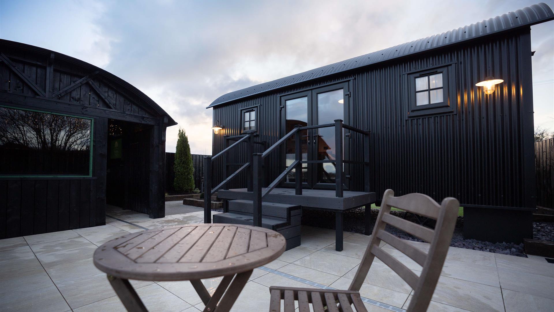 exterior view of the Lodge with outdoor wooden chair and table on paved patio area.