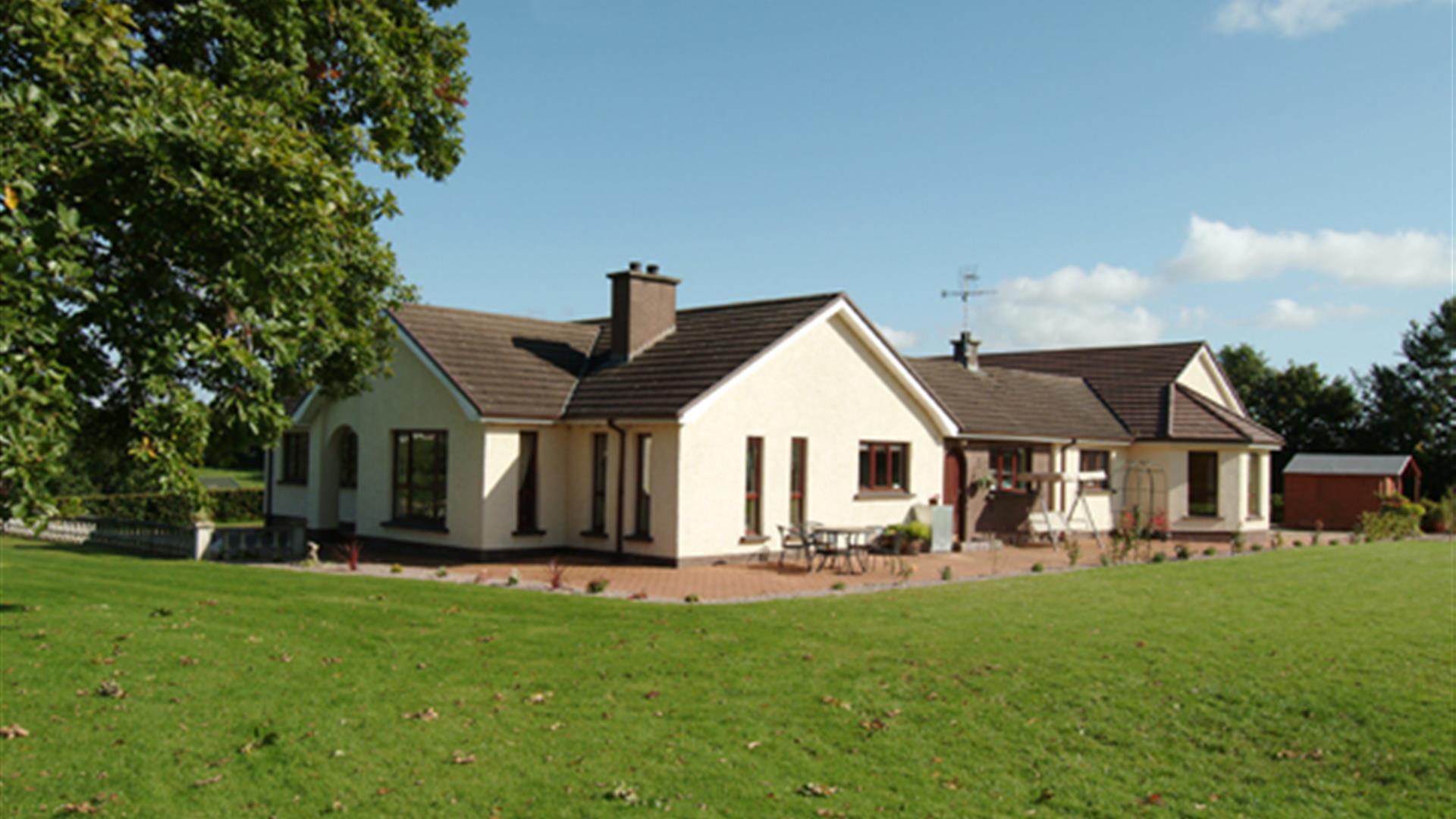 Outside view of house with patio area and large garden