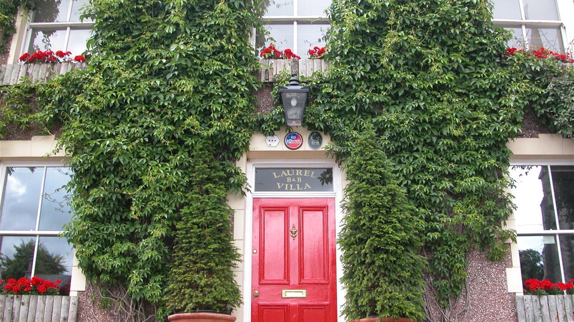 Outside image of Laurel Villa with greenery on walls and red door