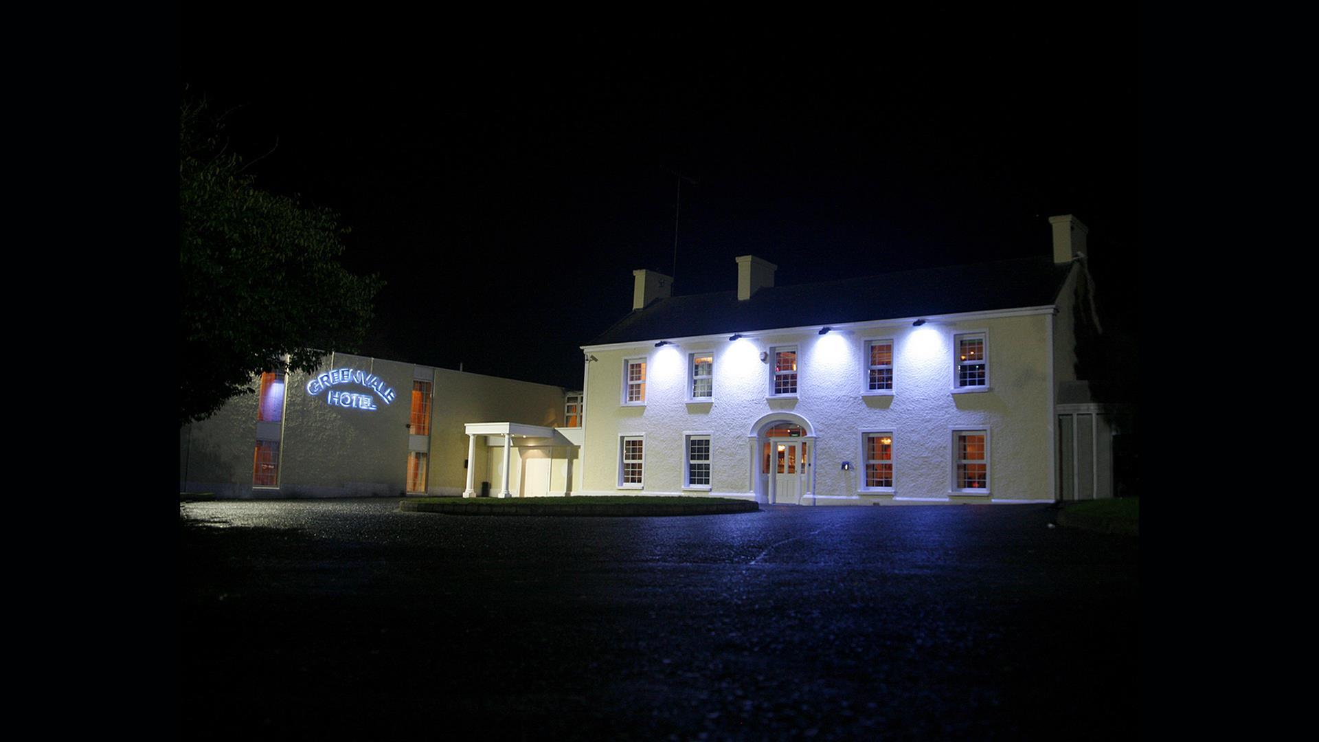 Image of a large two story building lit with four flood lights