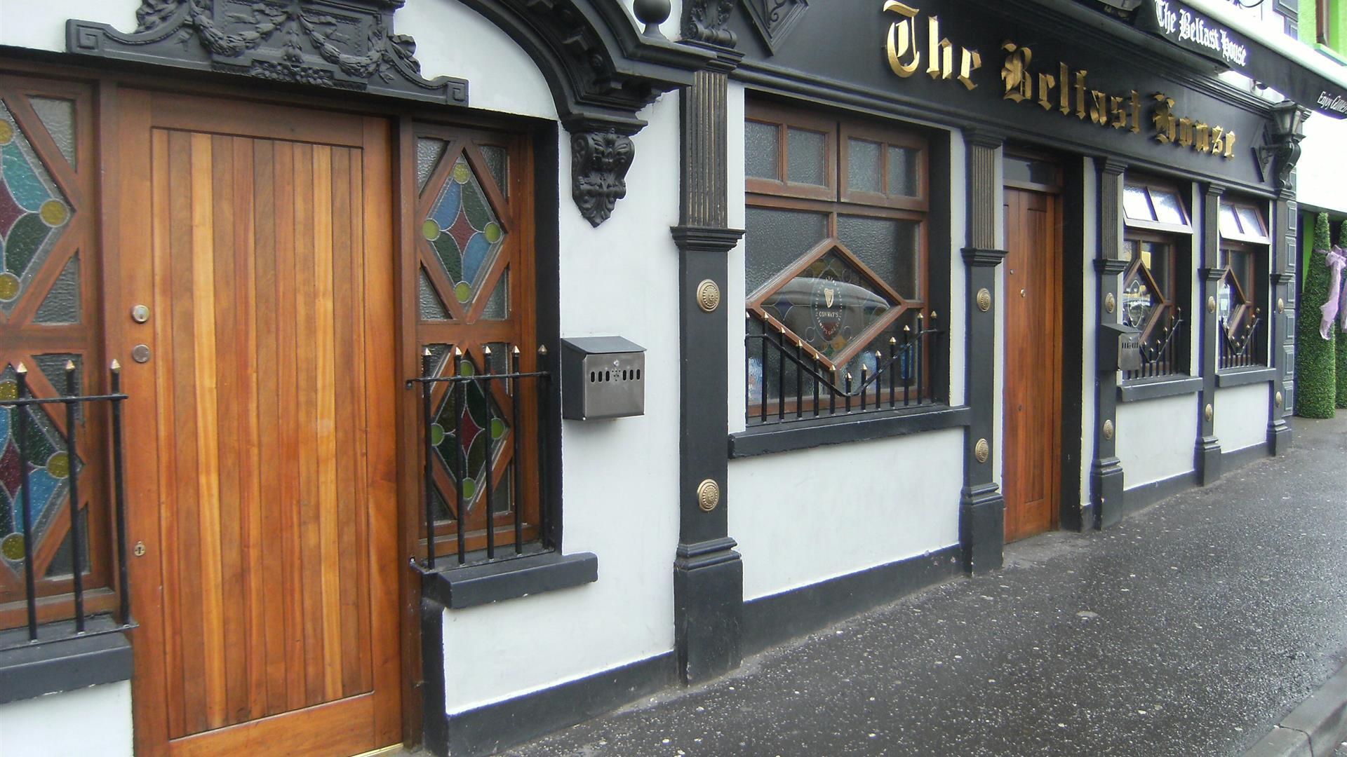 A white building with ornate black features and a wooden door