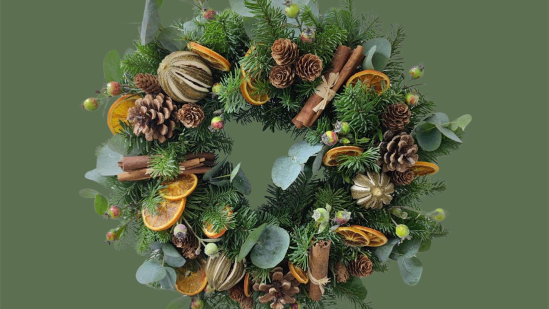 Image of a Christmas wreath with dried oranges, cinnamon sticks and pine cones.