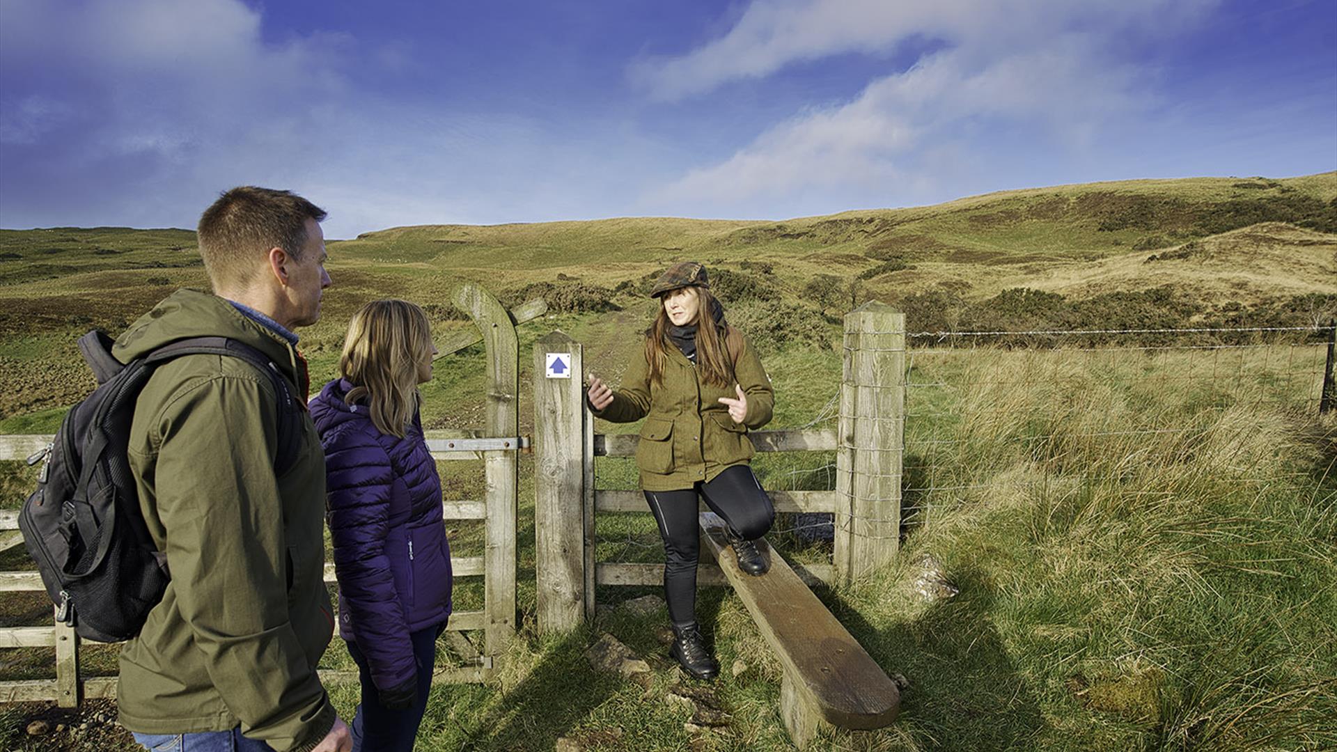 A couple at a gate with a tour guide in the Sperrin Mountains