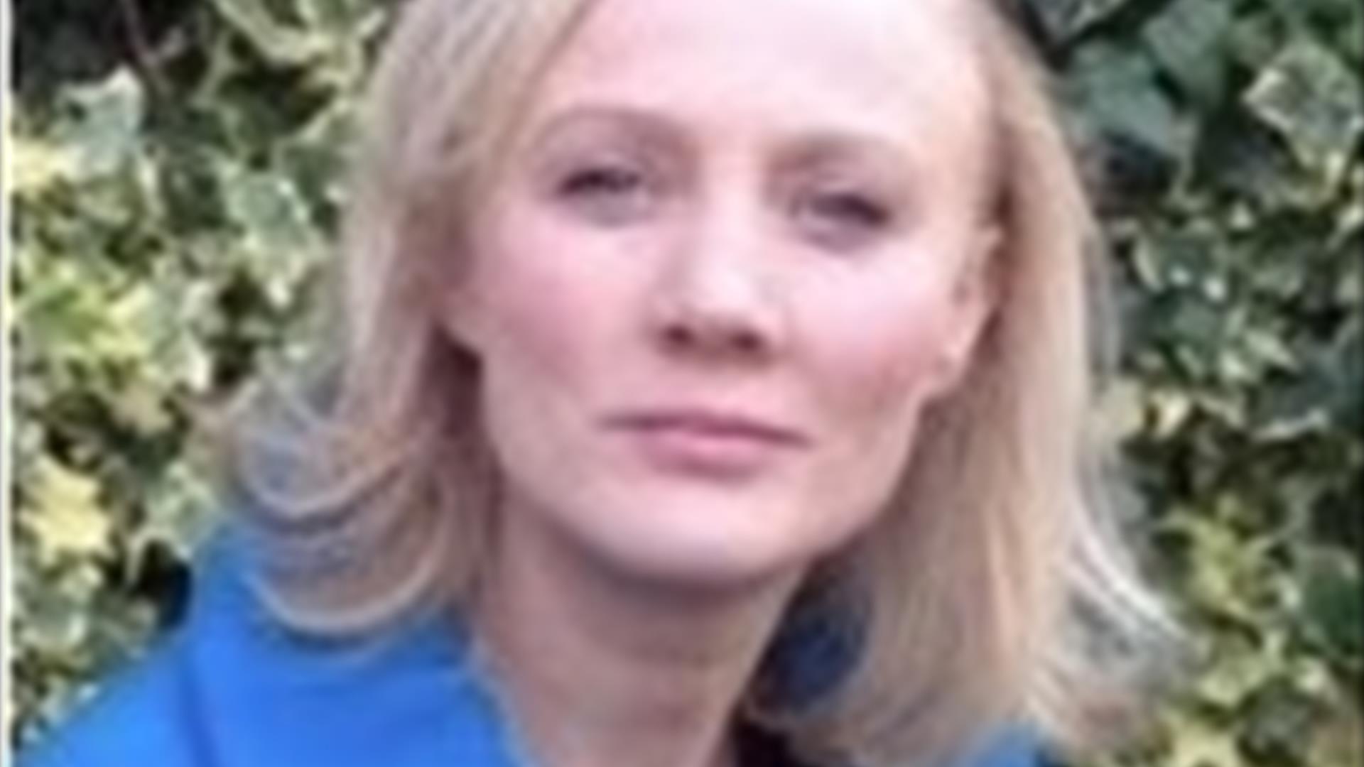 Image of Anne Quinn who has blonde shoulder length hair and wearing a blue jacket