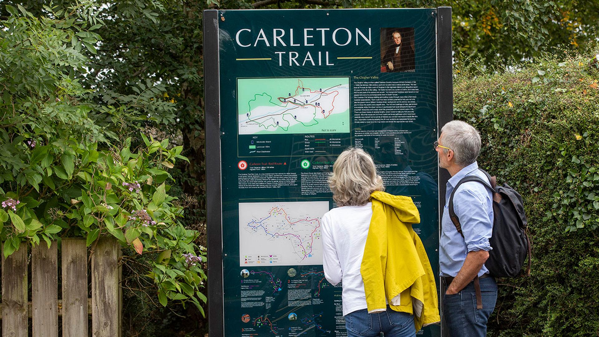 A mature couple looking at a sign on the Carleton trail in the Clogher valley.