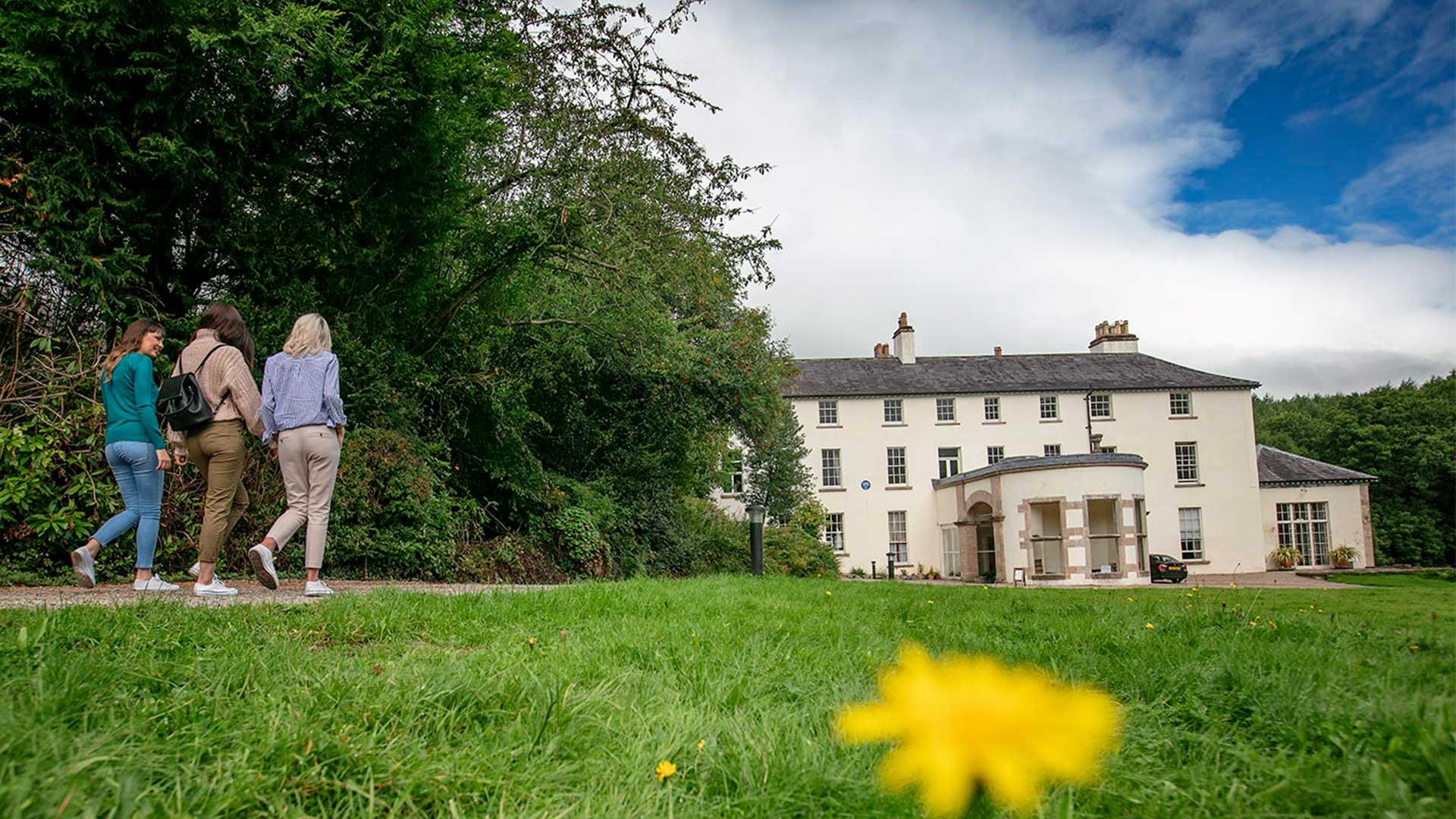 Three girls walking towards Lissan house on a sunny day