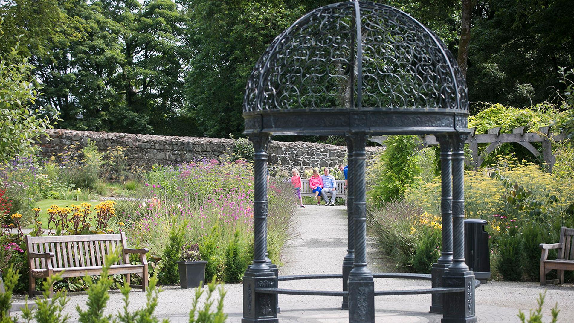 A couple and young child pictured through the arbour in Maghera Walled Garden.