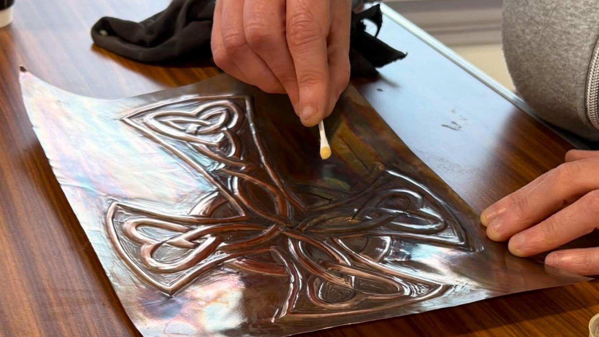 Photo of someone handcrafting a piece of copper