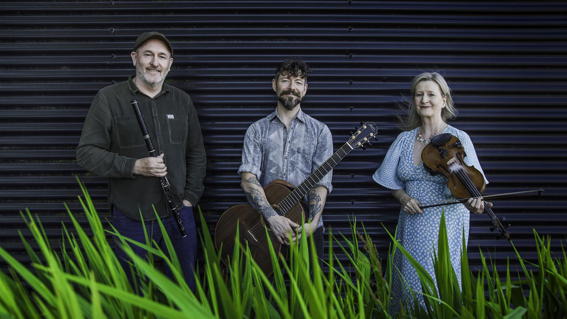 2 men and 1 lady holding their traditional instruments - guitar, fiddle and flute