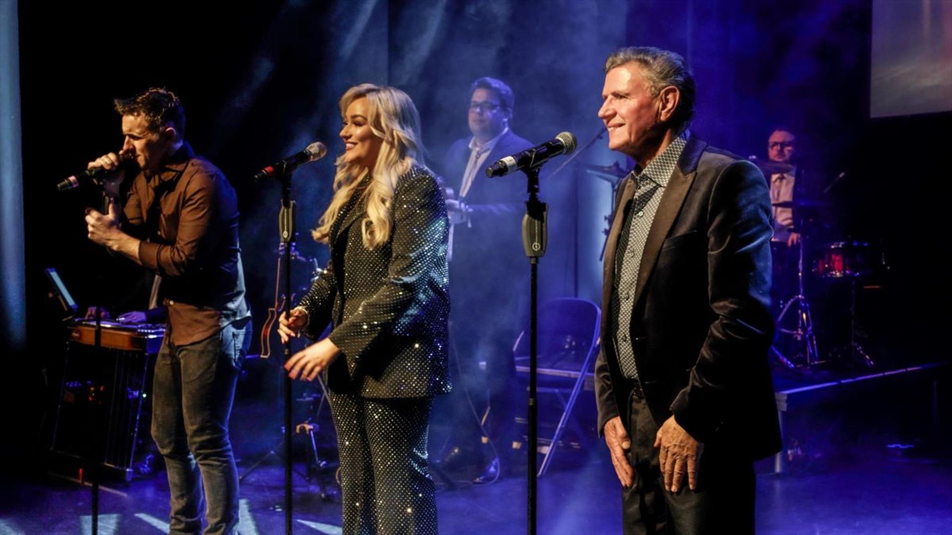 An image of Johnny Brady, Claudia Buckley and John Hogan on stage singing
