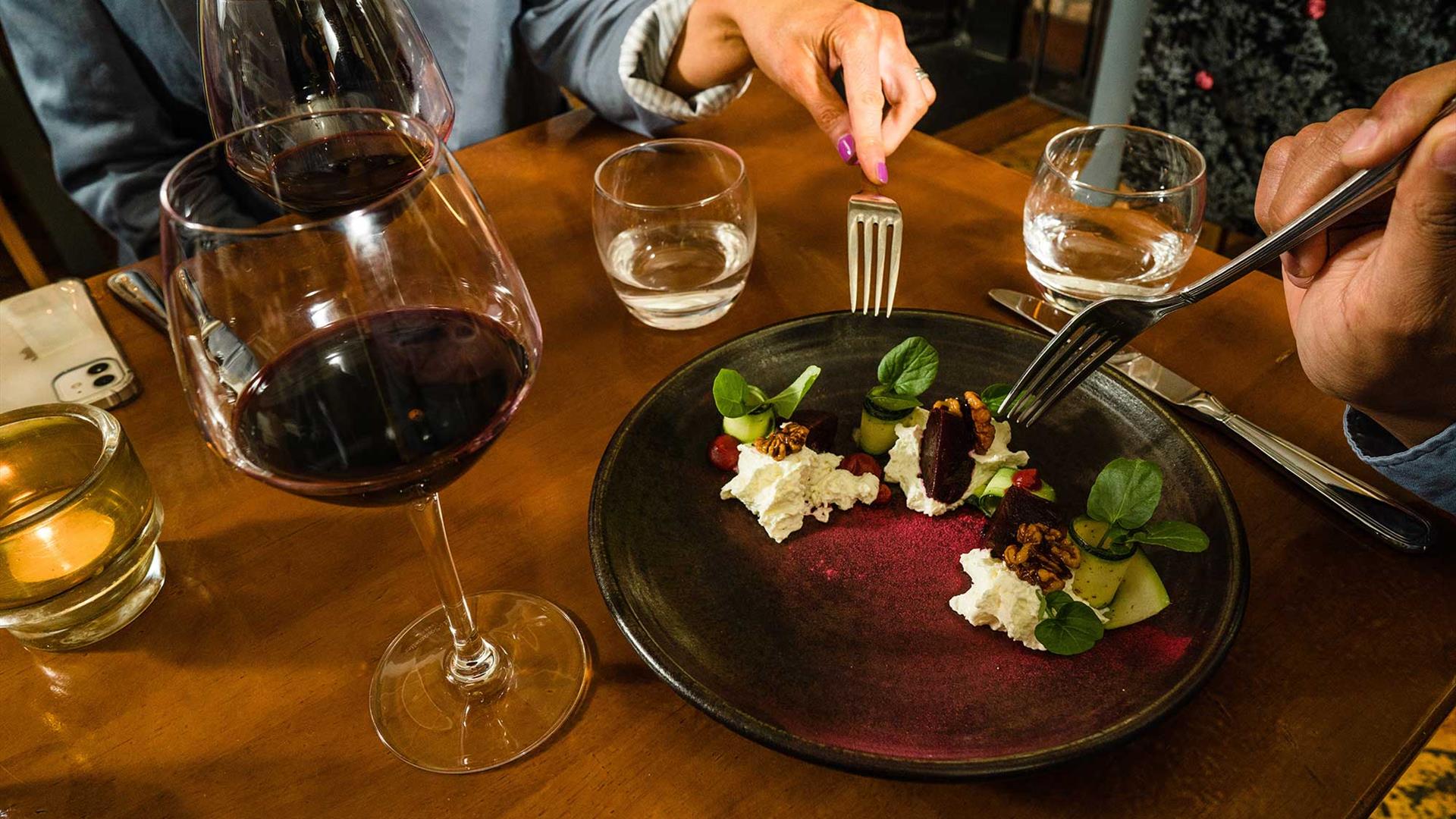 A plate of food and glass of red wine