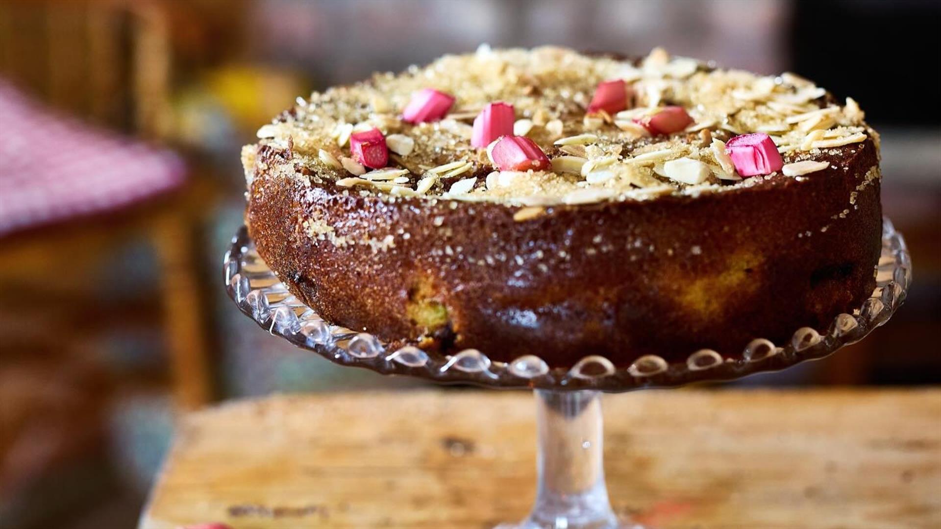 Image of a cake on a glass cake stand with rhubarb on top