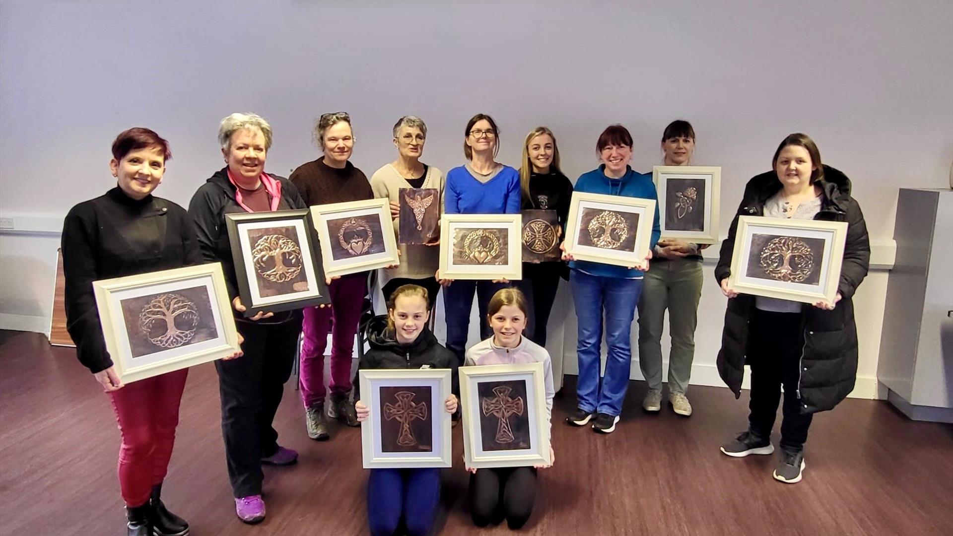 Image of a group of people holding up there copper crafts
