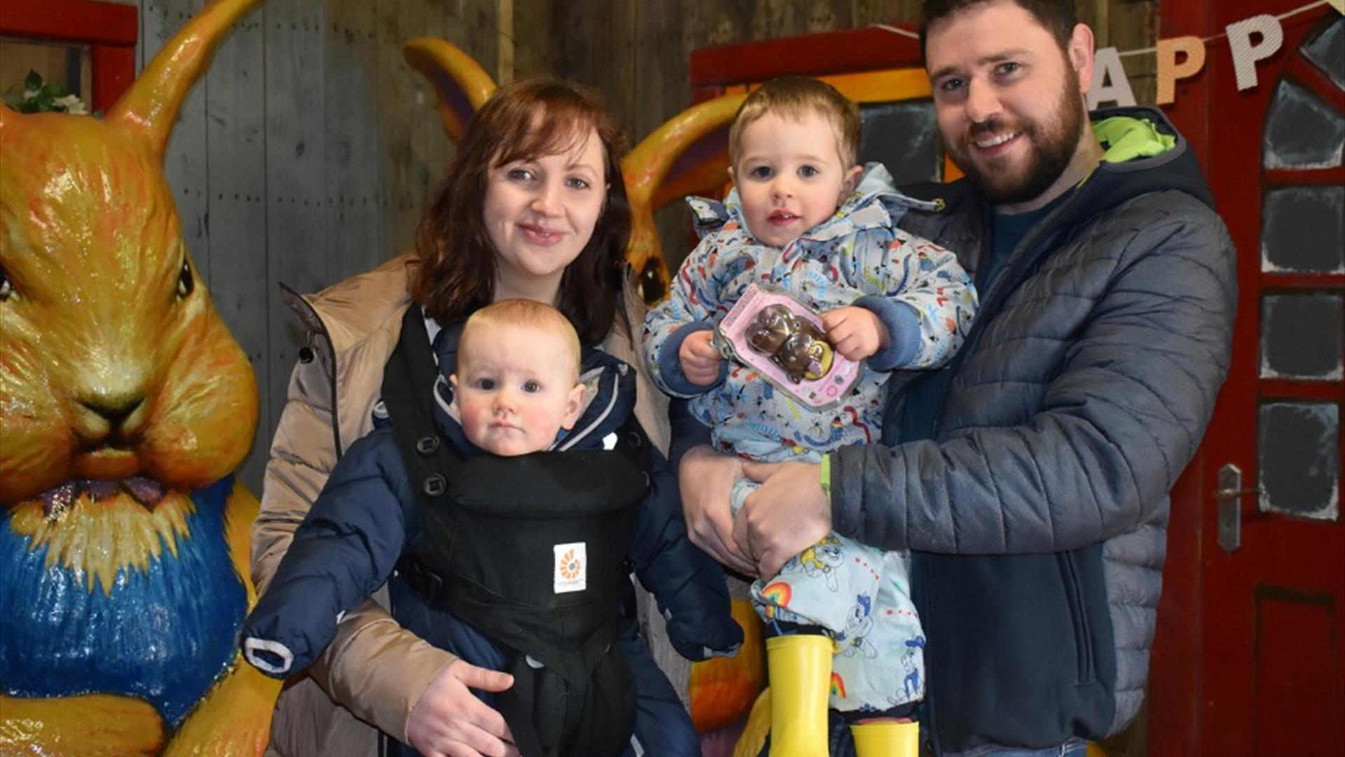 Image of two adults and two kids in front of a plastic bunny rabbit