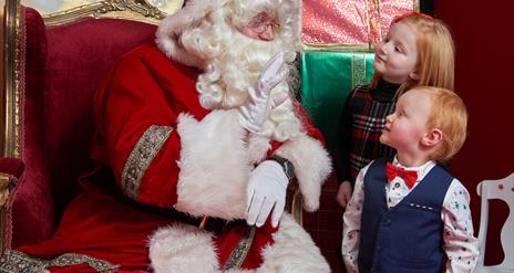 Two children talking to Santa in his grotto