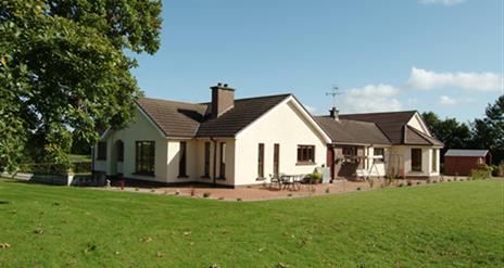 Outside view of house with patio area and large garden