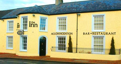 Outside image of The Inn with yellow walls and a black door