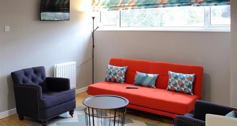 living area with orange sofa and 2 navy armchairs