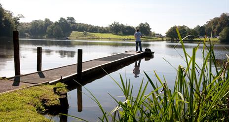 A man standing fishing on the jetty at Dungannon park lake