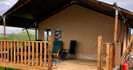 The outside of the tent with a covered deck and chairs